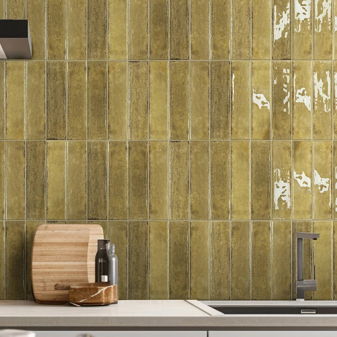 Kitchen with green tiled wall, stove, cutting board, and coffee maker.