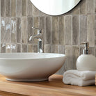 Bathroom vanity with a white sink, wooden countertop, and tiled wall.